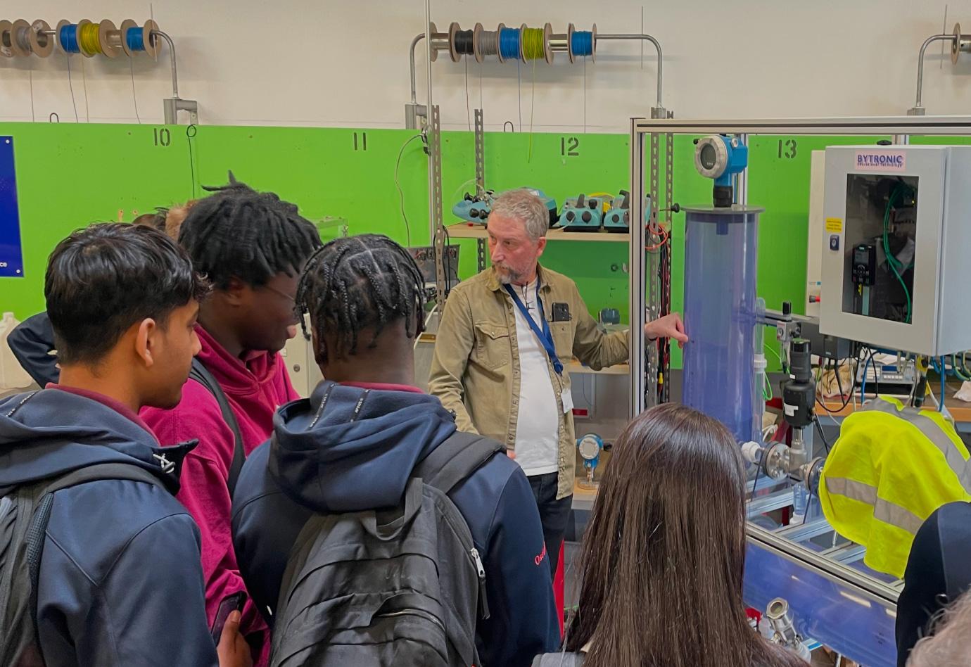 A man showing young people around some machinery